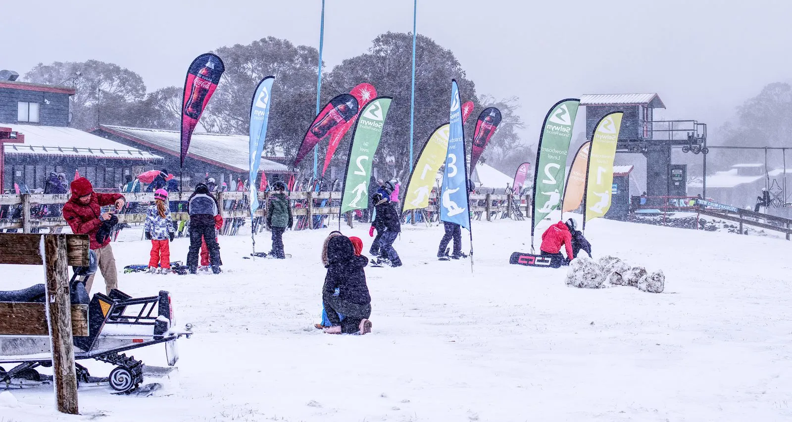 A snowy day at a ski resort with families enjoying winter activities outdoors.